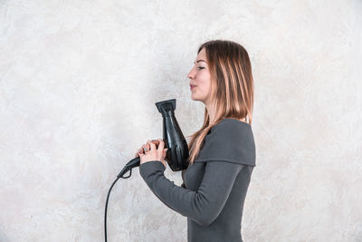 Side view of woman standing against wall