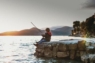 Man fishing in sea against sky