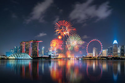 Firework display over illuminated buildings in city at night