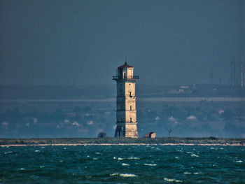 Lighthouse by sea against sky