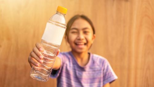 Mid adult woman holding glass bottle