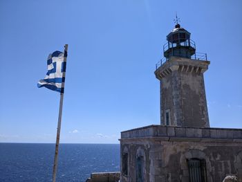 Low angle view of lighthouse by sea against clear sky