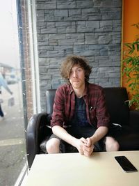 Portrait of handsome young man sitting on sofa at home