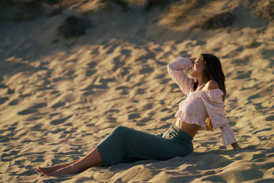 Side view of woman relaxing on sand at beach