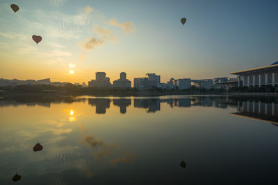 Reflection of hot air balloon in lake at sunset