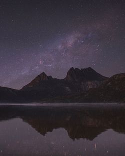 Scenic view of mountain by lake against sky at night