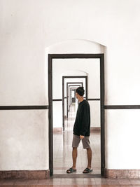 Rear view of young man looking through window