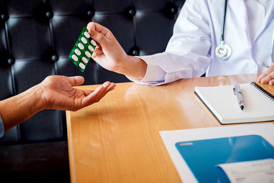 Midsection of doctor giving medicine to patient in hospital