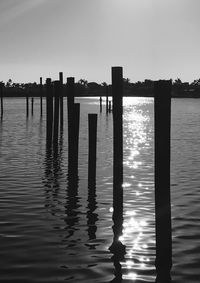 Wooden posts in lake against sky