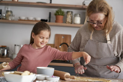 Grandma and granddaughter rolling dough