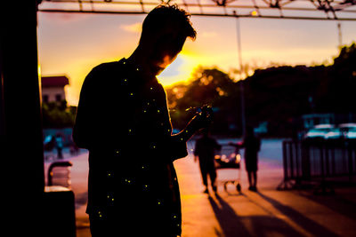 Silhouette woman photographing at sunset