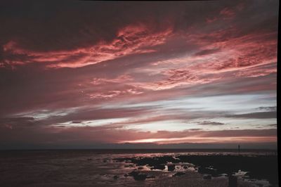 Scenic view of sea against dramatic sky during sunset