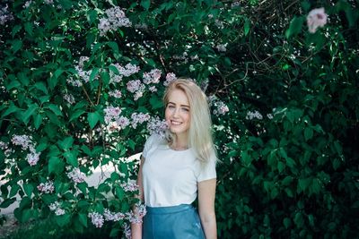 Portrait of smiling young woman standing against plants