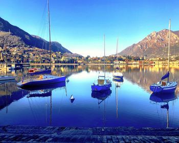 Sailboats moored in lake against sky