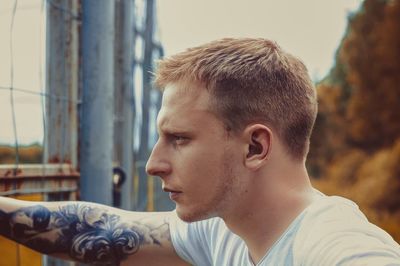 Side view of thoughtful man leaning on fence