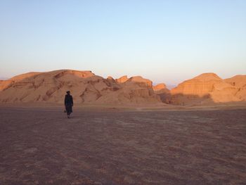 Rear view of woman standing on arid landscape