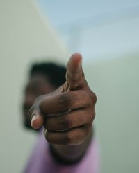 Close-up of human hand against sky