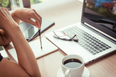 Cropped hands of businesswoman sitting at desk in office