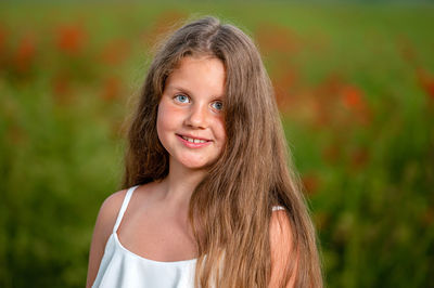 Portrait of a little girl against the background of a field of poppies in the evening sunlight