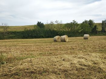 Hay bales on field against sky