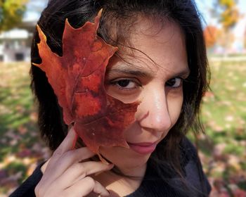 Close-up portrait of a smiling young woman holding leaf