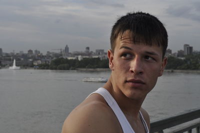 Close-up of thoughtful man standing against river during sunset