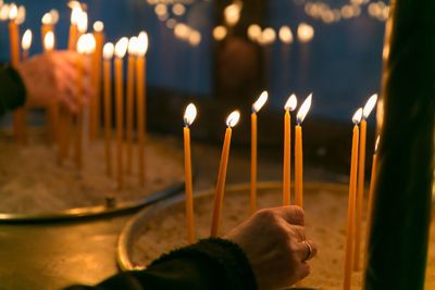 Human hand holding lit candles against temple