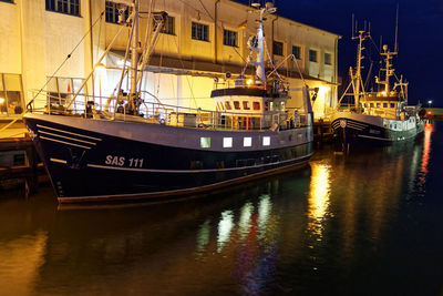 Boats moored at harbor against sky at night