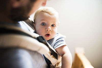 Happy father with baby in baby carrier at home