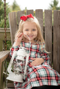 Portrait of cute smiling girl holding lantern sitting on swing