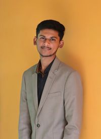 Portrait of young man standing against yellow background