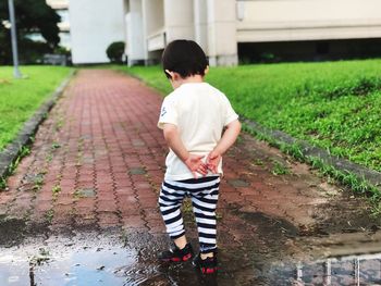 Rear view of boy standing on footpath