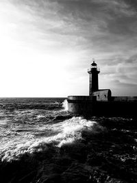 Lighthouse by sea against sky