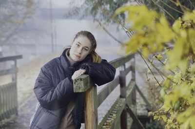 Portrait of young woman standing against plants