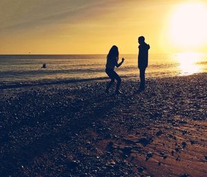 Silhouette of people on beach at sunset