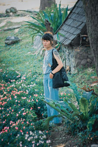 Portrait of young woman standing against plants