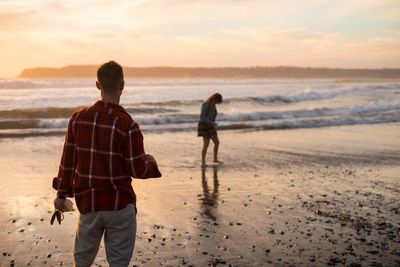 Woman standing on beach at sunset