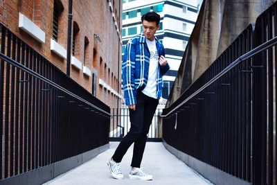 Full length of young man standing on railing against building