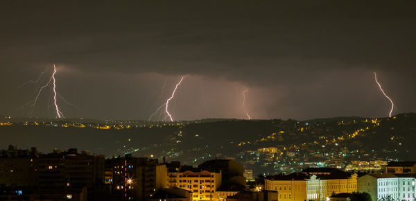 Lightning over illuminated cityscape at night