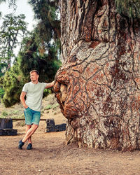 Full length portrait of young man standing against trees