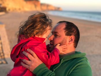 Mid adult man lifting daughter at beach