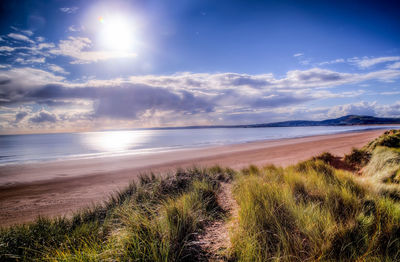 Scenic view of beach against cloudy sky