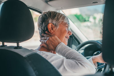 Side view of young man sitting in car