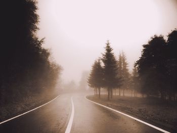 Road amidst trees against clear sky