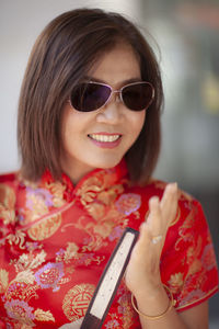 Portrait of smiling woman gesturing while standing outdoors