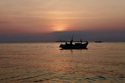 Silhouette boat in sea against sky during sunset