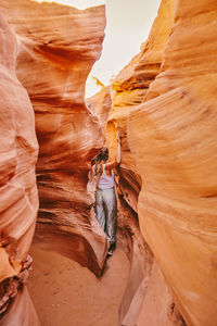 Young woman exploring narrow slot canyons in escalante, during summer