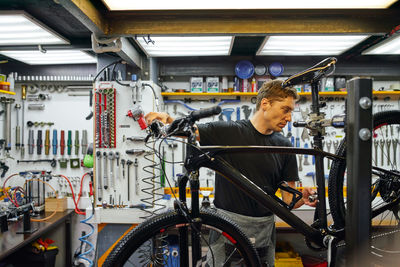 Focused male technician attaching wheel to bike while working in professional modern workshop