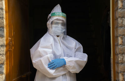 Portrait of woman wearing protective suit standing against wall