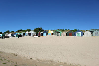 Brightly coloured beach huts positioned in a row at the top of a beautiful abersoch beach